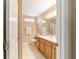 Bright bathroom featuring a wood vanity, neutral tile flooring and walls, and a decorative mirror with lighting at 1029 Sw 157Th Ln, Ocala, FL 34473