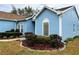 A charming blue home features a glass block window and mature landscaping at 11484 Sw 76Th Cir, Ocala, FL 34476