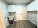 The laundry room with a utility sink, storage cabinets, and access to the outside at 11484 Sw 76Th Cir, Ocala, FL 34476