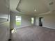 Expansive carpeted bedroom featuring a tray ceiling and windows at 13418 Sw 60Th Court Rd, Ocala, FL 34473