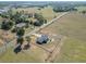 A far aerial view reveals the home nestled within an expansive rural landscape along a country road at 13800 Se 80Th Ave, Summerfield, FL 34491