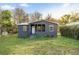 Cozy gray house with a covered front porch and white trim, surrounded by a green lawn and mature trees at 21055 Highway 441 N, Micanopy, FL 32667