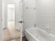 Bathroom with white tiled bathtub next to a doorway leading to a bedroom at 29 Guava Pass, Ocklawaha, FL 32179