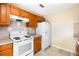 Kitchen with white appliances, wood cabinets, tile backsplash and floors at 434 Bar Ct, Kissimmee, FL 34759