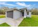 Single-story home showcasing gray exterior, gray garage door, a walkway, and a green lawn at 47 Sequoia Loop, Ocklawaha, FL 32179