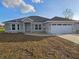 Home's facade with a two-car garage, complemented by well-maintained lawn and a charming front entrance at 5500 Sw 151St Street Rd, Ocala, FL 34473