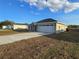 Home's front yard featuring a driveway leading to a two-car garage, complemented by a well-maintained lawn at 5500 Sw 151St Street Rd, Ocala, FL 34473