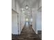 Long hallway featuring wood-look floors leading to a large living area and kitchen at 5500 Sw 151St Street Rd, Ocala, FL 34473