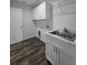 Laundry room features white cabinets, a sink, and wood look flooring at 5500 Sw 151St Street Rd, Ocala, FL 34473