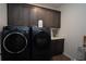 A laundry room features dark wood cabinetry, countertop space, and modern washer and dryer units at 6367 Sw 70Th Cir, Ocala, FL 34474