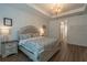 A staged main bedroom is accented by a chandelier, side tables, and a patterned bedspread at 6367 Sw 70Th Cir, Ocala, FL 34474