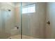 Close-up of luxurious glass-enclosed shower featuring pebble flooring and window at 6367 Sw 70Th Cir, Ocala, FL 34474