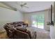 Cozy living room features a ceiling fan, leather furniture, and sliding glass doors to the backyard at 6950 Se 124Th Ln, Belleview, FL 34420