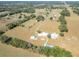 Aerial view of a sprawling rural property featuring a home, barns and fields surrounded by trees at 7688 Se 135Th St, Summerfield, FL 34491