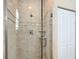 Tiled shower with glass door features shower head, faucet, and shelving at 7688 Se 135Th St, Summerfield, FL 34491