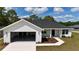 Charming white single story house with an attached two car garage, manicured lawn, and dark gray roof at 8295 Se 159Th Ln, Summerfield, FL 34491