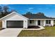 Charming single-story home with a two-car garage, green lawn and modern black and white color scheme at 8295 Se 159Th Ln, Summerfield, FL 34491