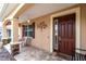 Cozy front porch featuring a dark wood door, decorative metal art, and brick-style accents under the porch at 8532 Sw 79Th Ave, Ocala, FL 34481