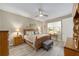 A well-lit main bedroom features a wood bed frame, ceiling fan, and view of a large window at 8874 Sw 104Th Cir, Ocala, FL 34481