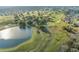 Scenic aerial view of a golf course with a beautiful pond, lush greenery, and well-manicured fairways at 9033 Se 136Th Loop, Summerfield, FL 34491