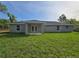 A view of the back of the home featuring a modest backyard and a covered patio area at 96 Fisher Way Trl, Ocklawaha, FL 32179