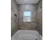 Bathtub shower featuring modern tile and a built-in shelf for storage at 96 Fisher Way Trl, Ocklawaha, FL 32179