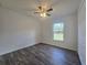 This bedroom features wood-look floors, a window with a view, and a ceiling fan at 96 Fisher Way Trl, Ocklawaha, FL 32179
