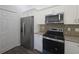 Stainless steel refrigerator and range complement the white cabinetry and granite countertops at 96 Fisher Way Trl, Ocklawaha, FL 32179