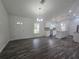 Open-concept living space featuring wood floors, a modern chandelier, and a view into the bright, updated kitchen at 96 Fisher Way Trl, Ocklawaha, FL 32179