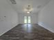 Bright living room featuring wood-look floors, a ceiling fan, and double doors to the backyard at 96 Fisher Way Trl, Ocklawaha, FL 32179