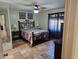 Cozy main bedroom featuring a queen-size bed, ceiling fan, decorative artwork, and a doorway to an en suite bathroom at 10831 Se 50Th Ter, Belleview, FL 34420