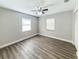 Bedroom featuring wood floors, a ceiling fan, and two windows, exuding comfort and practicality at 12461 Se 126Th Ct, Ocklawaha, FL 32179