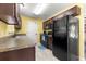 Well-equipped kitchen with dark wood cabinetry, laminate countertops, and a sleek black refrigerator at 13 Pine Course Radl, Ocala, FL 34472