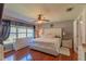 Bright main bedroom with white tufted headboard, ceiling fan and windows with backyard views at 13340 Se 86Th Cir, Summerfield, FL 34491