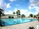 Large outdoor swimming pool with palm trees, blue sky, lounge chairs and a pool house for residents' enjoyment at 13625 Se 93Rd Court Rd, Summerfield, FL 34491