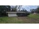 Outbuilding exterior with wood siding, concrete pad, one door and a roll up door at 14805 Se 51St Ct, Summerfield, FL 34491