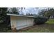 Outbuilding exterior with wood siding, concrete pad, one door and a roll up door at 14805 Se 51St Ct, Summerfield, FL 34491