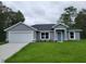 Beautifully renovated single-story home with a blue door, white trim, and lush green lawn at 20079 Sw 84 St, Dunnellon, FL 34431