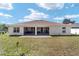 Rear view of the house showcasing the covered patio and spacious yard at 3925 Ne 58Th Cir, Silver Springs, FL 34488