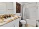 Bathroom with a unique countertop, sink, toilet and bath-shower combination with white tile at 3925 Ne 58Th Cir, Silver Springs, FL 34488