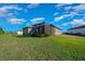 Back exterior view of a home featuring a screened lanai, well-maintained lawn, and manicured landscaping at 6185 Sw 89Th Ct, Ocala, FL 34481