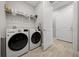 Well-lit laundry room boasts a washer, dryer, storage shelf, and an ironing board at 6185 Sw 89Th Ct, Ocala, FL 34481