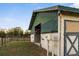 Barn with a green roof featuring stalls, barn doors, and adjacent pasture at 6890 Nw 21St St, Ocala, FL 34482