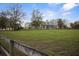 Sprawling ranch-style home set on a large grassy lot with wood fencing, mature trees, and blue sky at 6890 Nw 21St St, Ocala, FL 34482