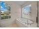 Bright bathroom featuring a soaking tub under a window with neighborhood views at 7151 Sw 96Th Ct, Ocala, FL 34481