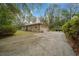 Side view showcasing the home's neutral exterior, expansive driveway, and landscaping, with trees enhancing privacy at 7810 Sw 186Th Cir, Dunnellon, FL 34432