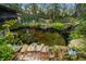 A beautiful pond is surrounded by greenery, rocks, and lawn ornaments in the backyard at 7810 Sw 186Th Cir, Dunnellon, FL 34432