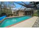 Enclosed pool area with a blue tiled pool, screen enclosure, and outdoor lounging space at 7810 Sw 186Th Cir, Dunnellon, FL 34432