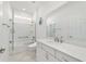 Bright bathroom with a glass-enclosed shower/tub combo, white vanity, and a large mirror at 8719 Sw 76Th Street Rd, Ocala, FL 34481