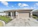 Single-story home featuring a well-manicured lawn, a large driveway, and a two-car garage at 8719 Sw 76Th Street Rd, Ocala, FL 34481